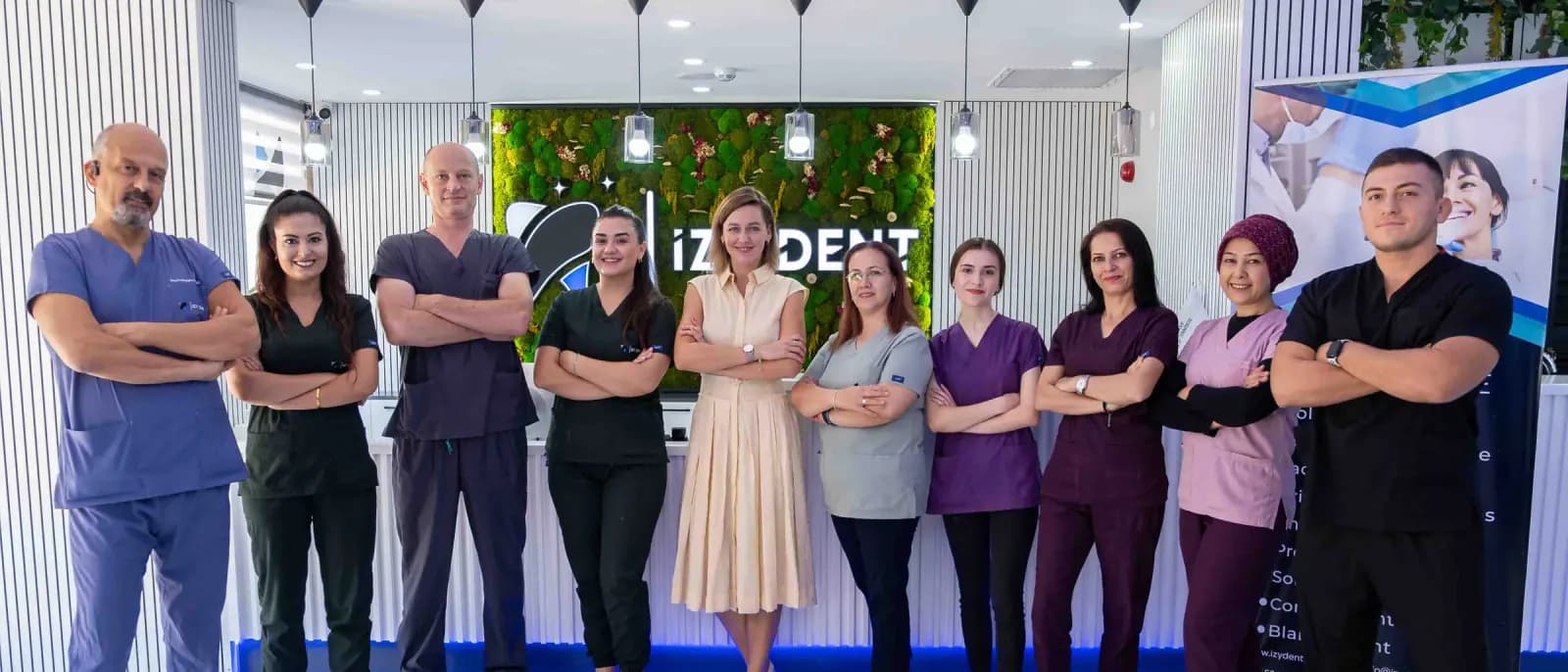 L'équipe d'İZY Dentiste devant le logo de la clinique